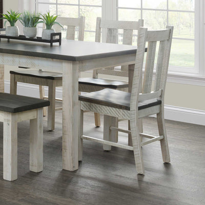 Distressed white slat-back dining chairs with gray wood seats tucked under the rustic two-tone Alamo dining table