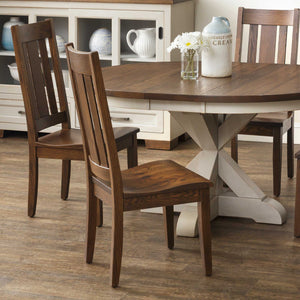 Oak mission slat back dining chairs around a round table with a white X pedestal base and daisies