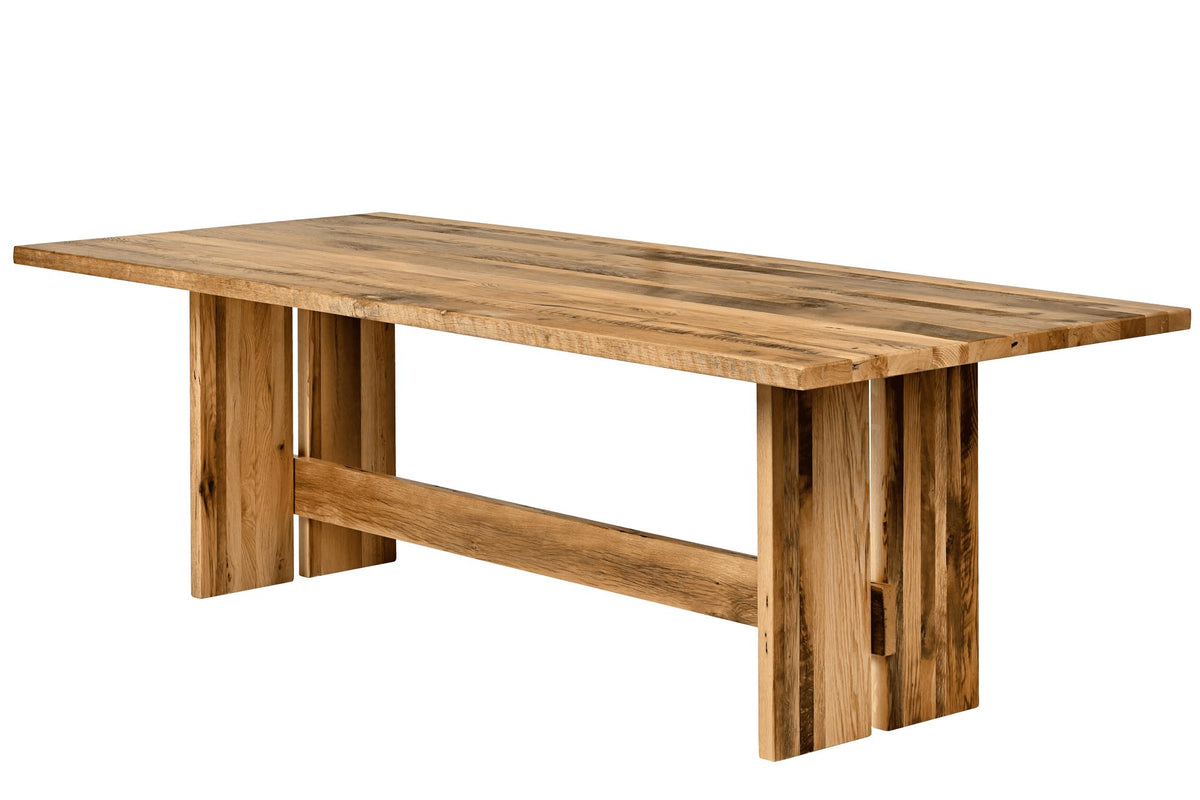 A rustic rectangular wooden dining table with a natural brown wood finish, featuring thick block legs and a horizontal support beam, shown on a plain white background.