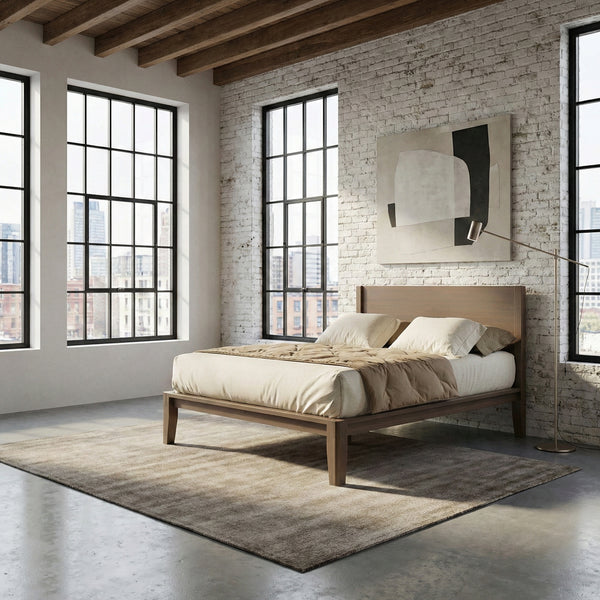 Solid wood platform bed with a flat panel headboard in a warm walnut finish, styled with linen bedding in a brick loft bedroom
