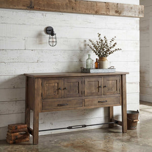 Weathered brown four-door sideboard with two drawers, iron knobs and turnbuckle stretcher against a whitewashed plank wall