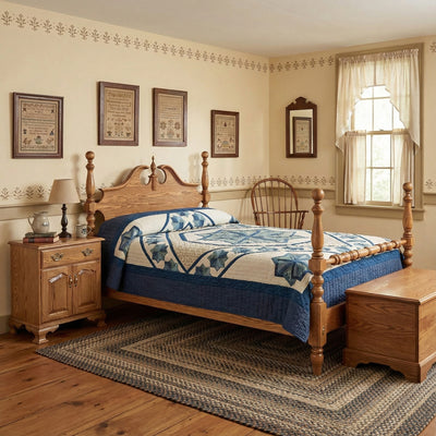 Oak cannonball post bed with a broken-arch pediment headboard and blue star quilt in a colonial bedroom with samplers