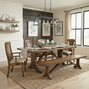 Rustic brown Westin trestle dining set with plank table, upholstered chairs, arm chair and bench in a farmhouse room
