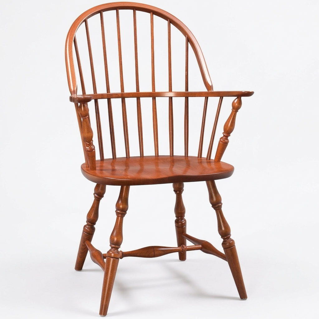 A classic wooden Windsor chair with a curved backrest, turned spindle legs, and a polished reddish-brown finish, photographed against a seamless white background.