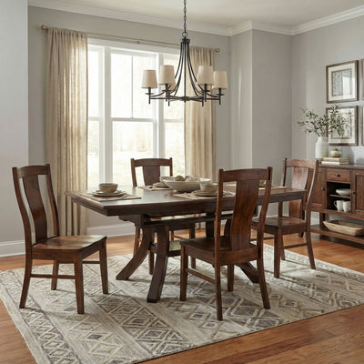 Christy trestle dining table in warm cherry finish set with six panel-back chairs under a black chandelier in a soft gray dining room