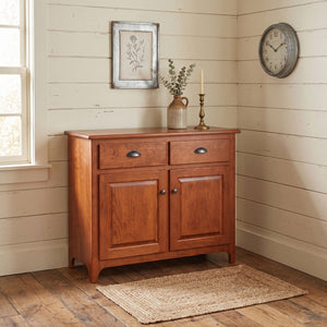 Cherry Plymouth two-door buffet with two drawers, cup pulls and raised panel doors styled in a shiplap corner