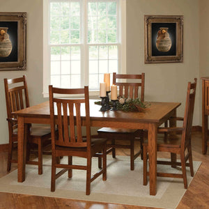 Mission style quartersawn oak leg dining table with slat back chairs, candles and greenery in a sunlit dining room