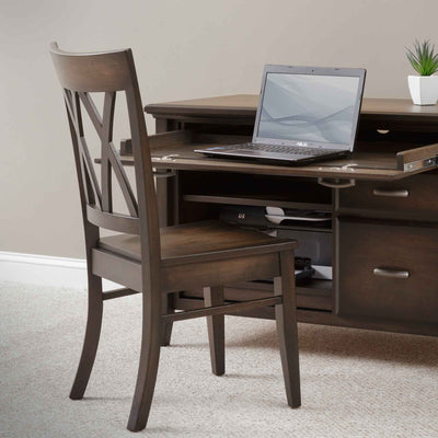 Wood office side chair with a double X back and saddle seat, pulled up to a credenza with a laptop