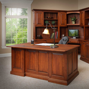 Back of the cherry executive desk showing finished raised panels, two wire grommets and a stepped base