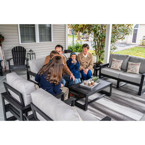 Family talking on black poly patio sofas with gray cushions around a coffee table on a porch
