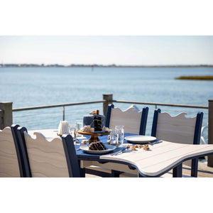 Close view of the wave carved chair backs and driftwood poly tabletop set with cake and glassware by the bay