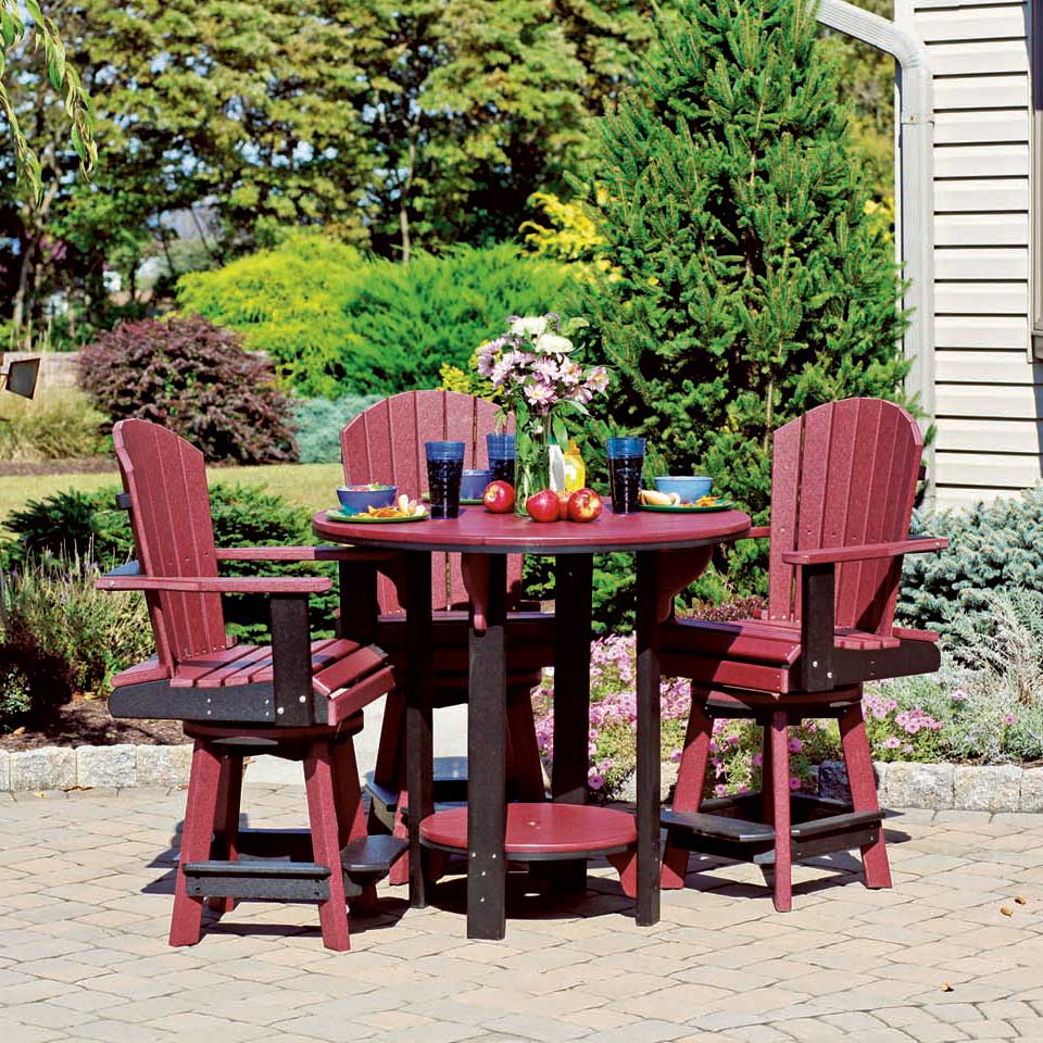 Cherrywood and black poly round pub table with swivel Adirondack chairs on a paver patio by evergreens