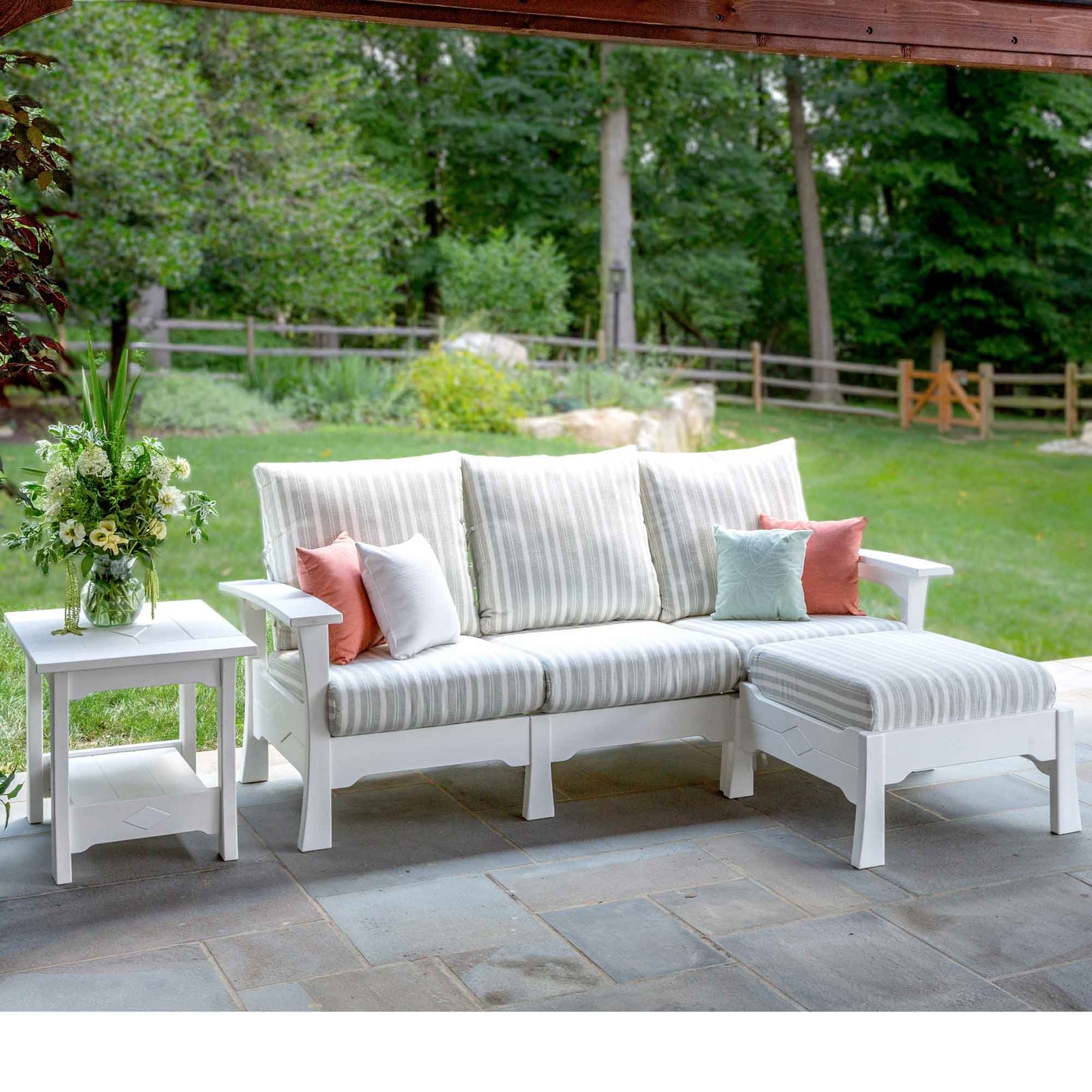 White poly patio sofa, chair and ottoman with soft striped cushions and a side table by a pool