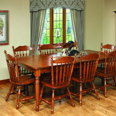 Traditional oak dining table with turned legs and six arrow spindle back chairs in a formal dining room by a bay window
