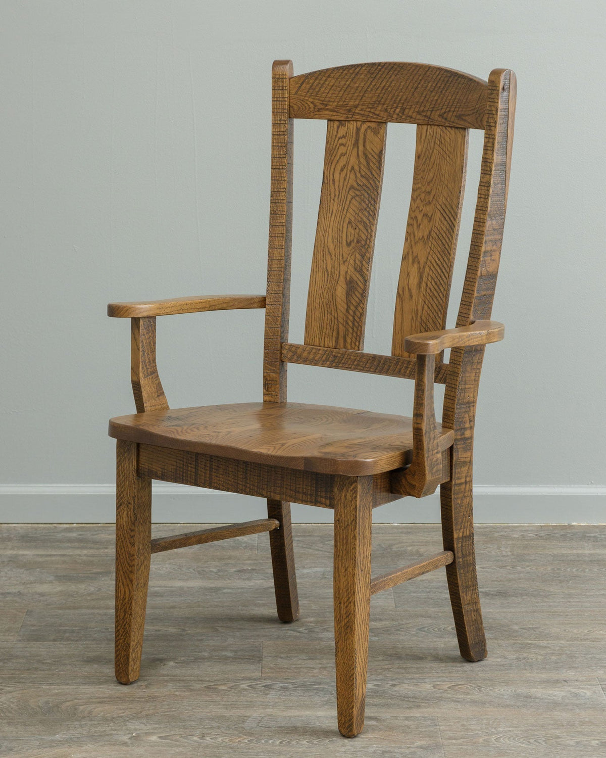 Rustic oak dining armchair with contoured two-slat back, scooped seat and rough-sawn texture in a burnished honey finish
