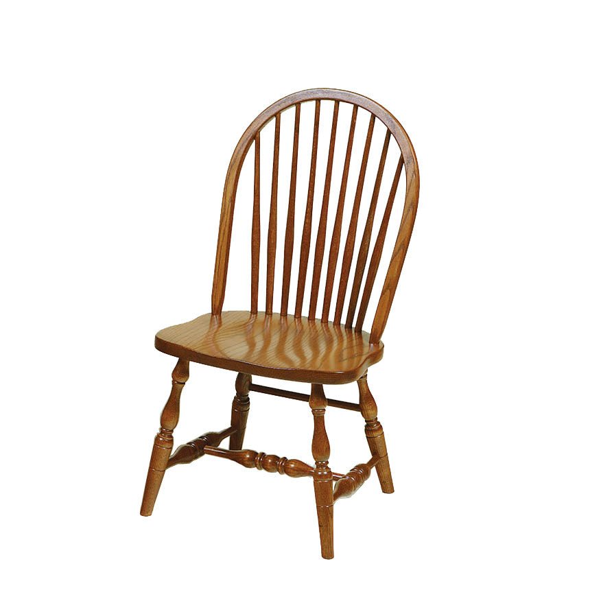 Oak Windsor dining chairs with bowed spindle backs and turned legs around a farmhouse table in a bright beamed dining room