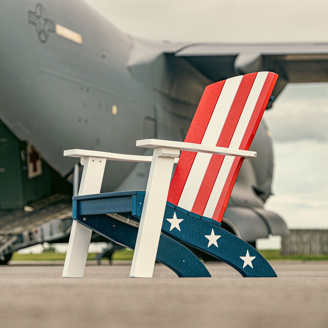 Patriotic poly Adirondack chair with red and white striped back, navy star-printed seat frame and white arms on a tarmac