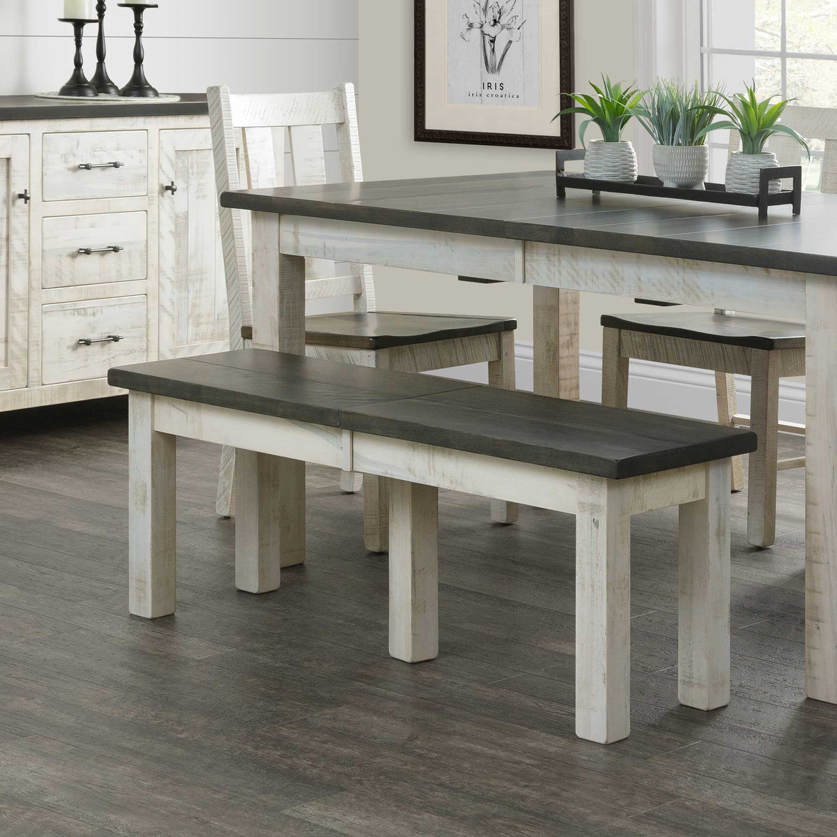 Two-tone dining bench with weathered gray plank top and distressed white legs beside a matching farmhouse table and stools