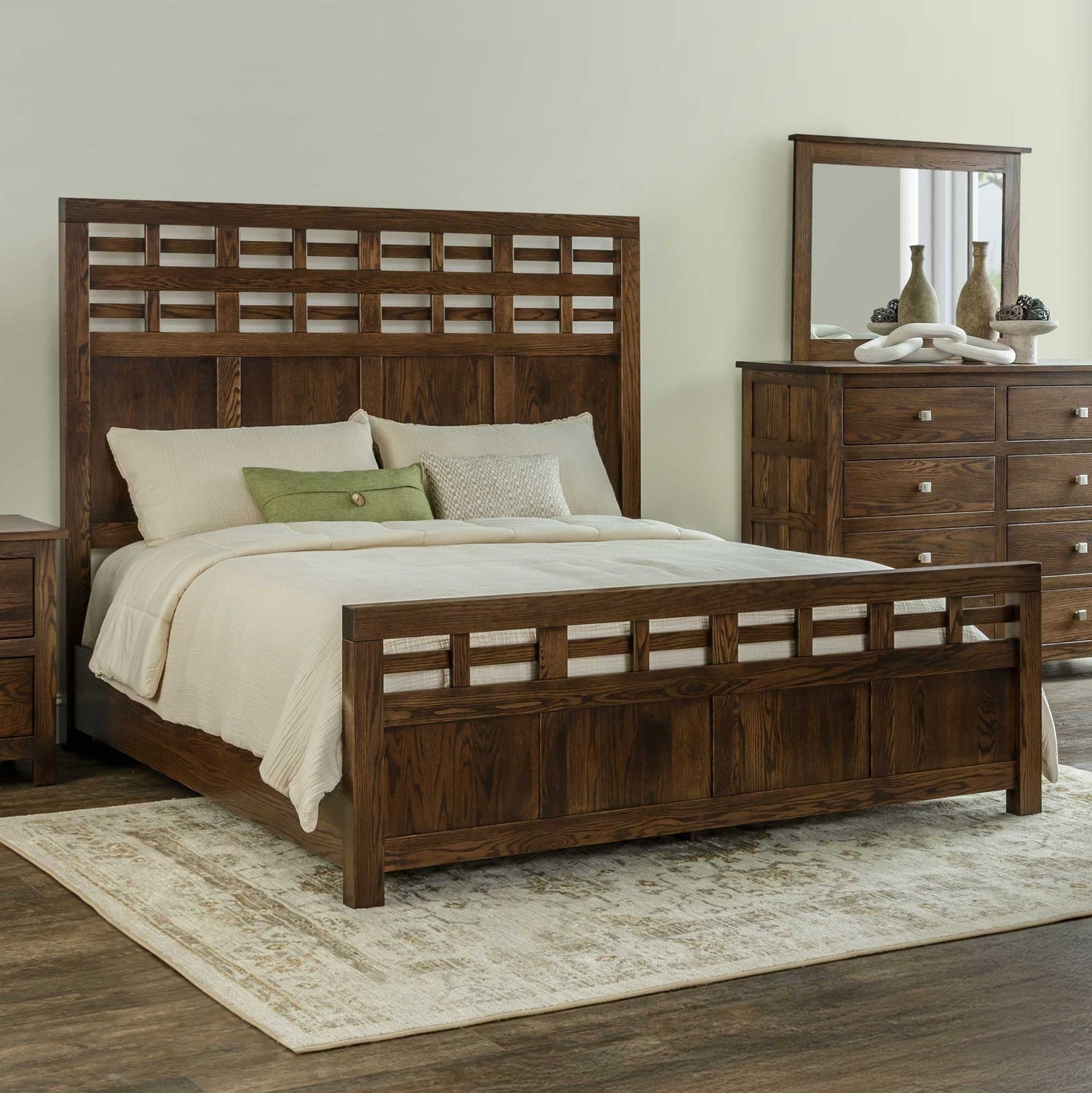 Alto lattice bed in dark oak with woven lattice headboard and footboard, styled with cream bedding beside a dresser and mirror