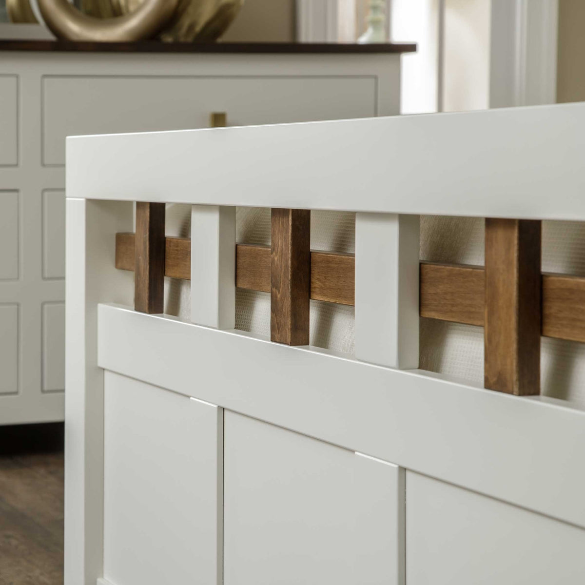 Close view of the white lattice footboard rail with warm brown wood cross pieces and recessed panels