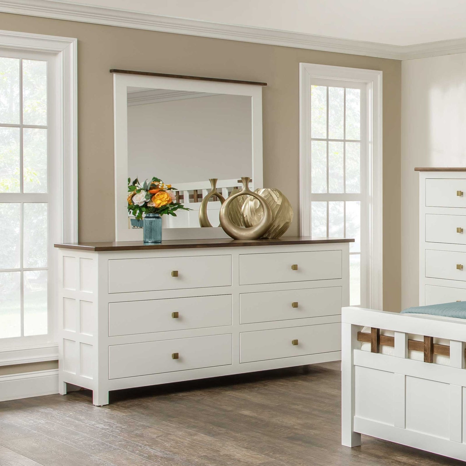 Cream painted six-drawer dresser with dark wood top and brass knobs under a mirror between two windows