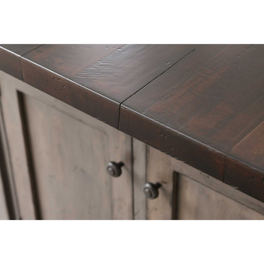 Corner detail of the dark plank island top overhanging a distressed gray cabinet with black door knobs