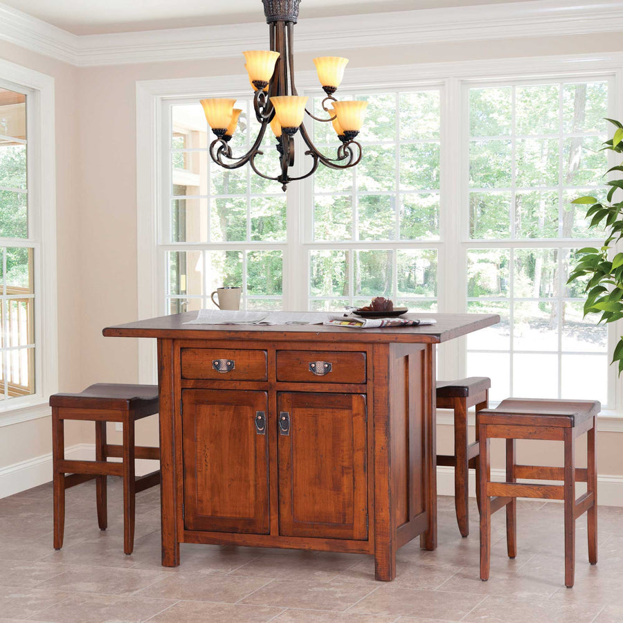 Cherry kitchen island set for four with two saddle stools under a chandelier in a window-lined breakfast room