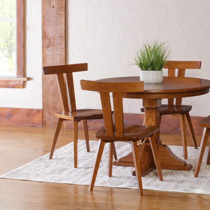 Dining set with a round cherry pedestal table and four T-back Astoria chairs beside a reclaimed wood window frame