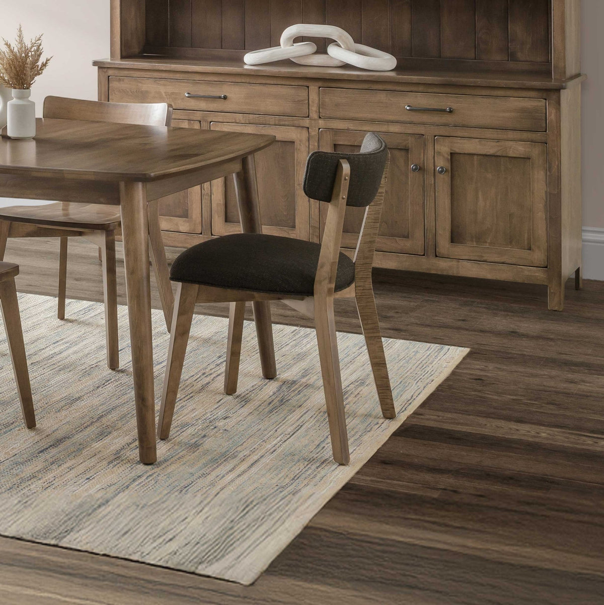 Mid century modern dining chair with a charcoal upholstered curved back and seat at a light wood table