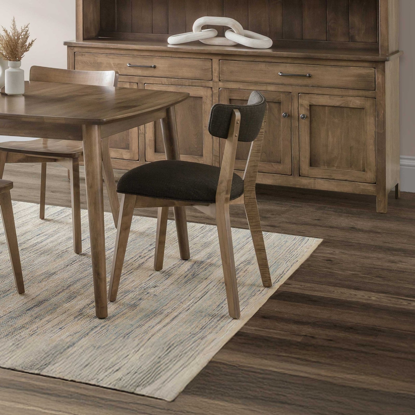Mid century modern dining chair with a charcoal upholstered curved back and seat at a light wood table
