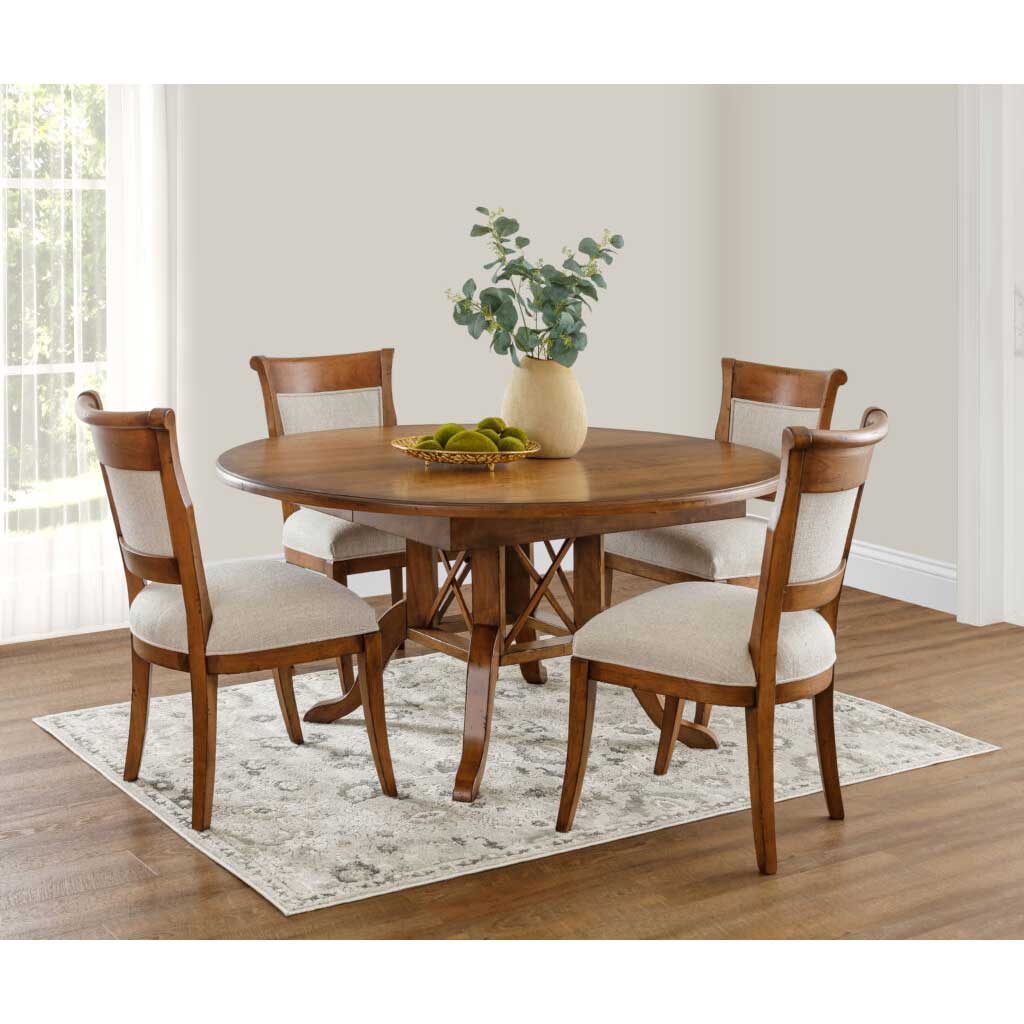 Round birdcage pedestal dining table in medium oak with four upholstered back chairs on a soft gray rug