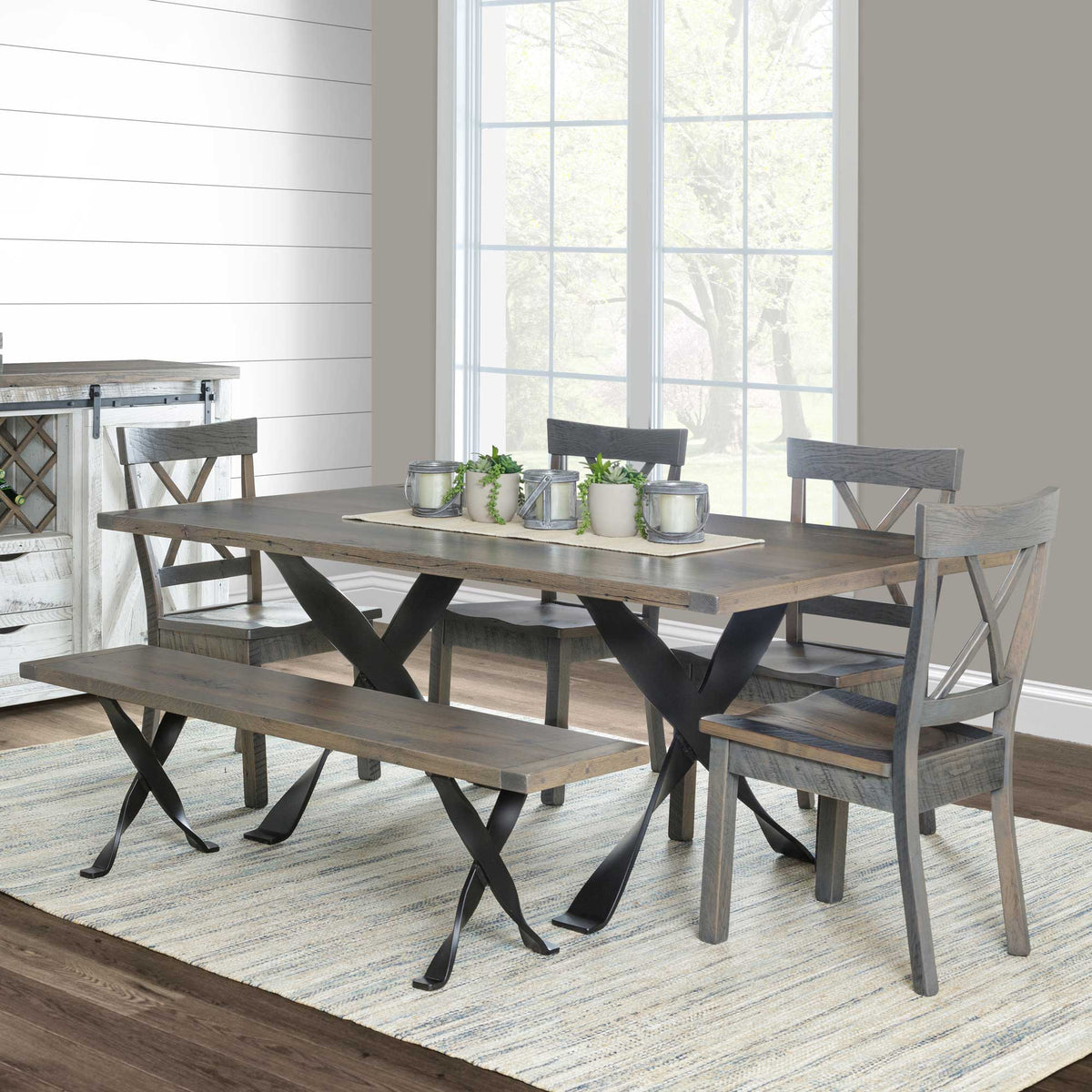 Gray reclaimed trestle dining table with twisted iron X base, four X back chairs and a matching bench