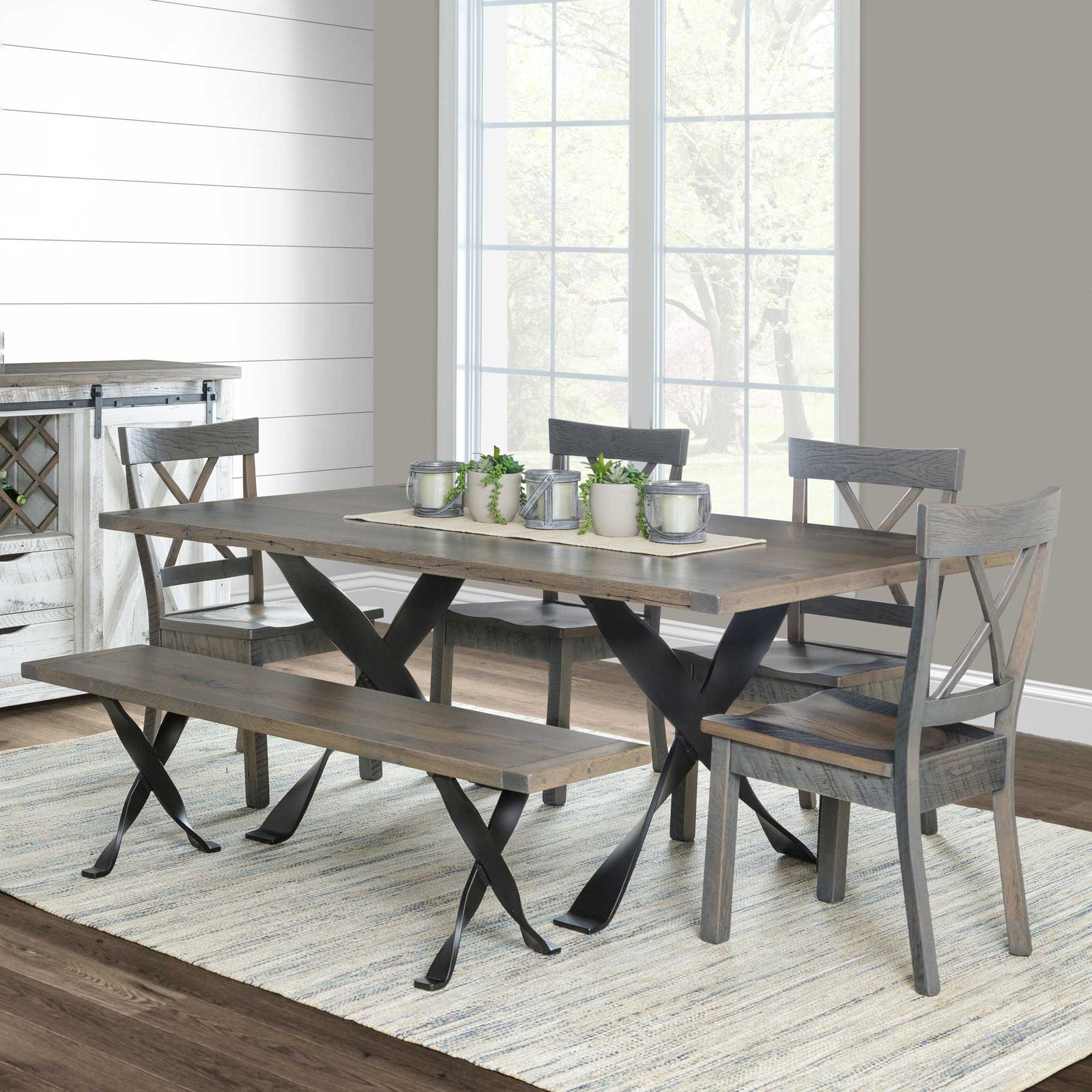 Gray reclaimed trestle dining set with iron X legs, four X back chairs and a bench in a shiplap dining room