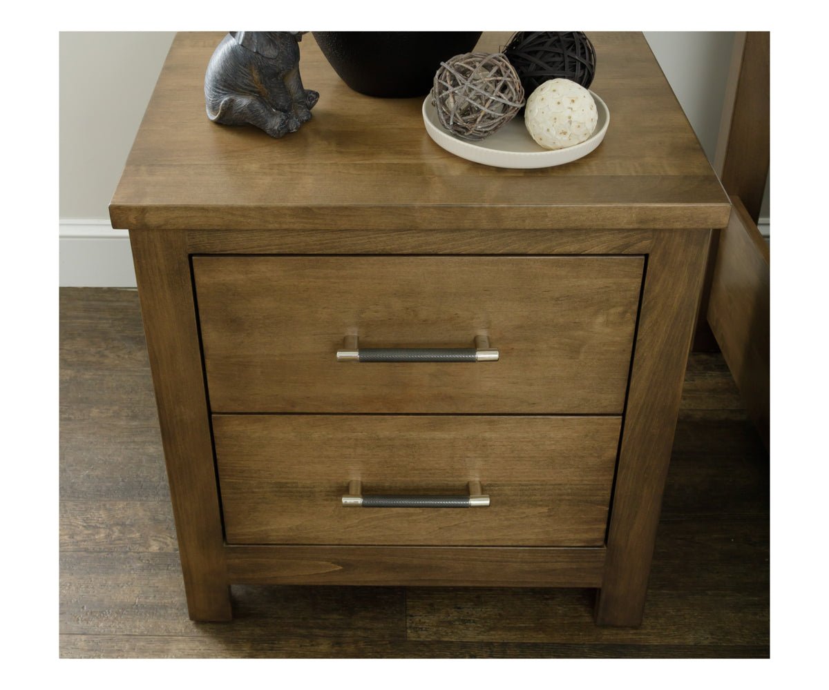 Close view of a light brown nightstand top with two bar pull drawers, a black vase and rattan balls