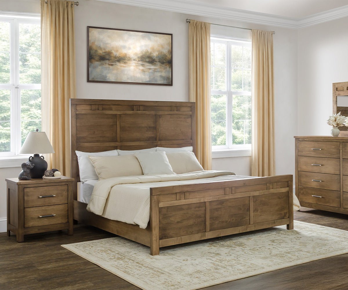 Brown maple panel bed with plank headboard and block accents, flanked by a nightstand under bright curtained windows