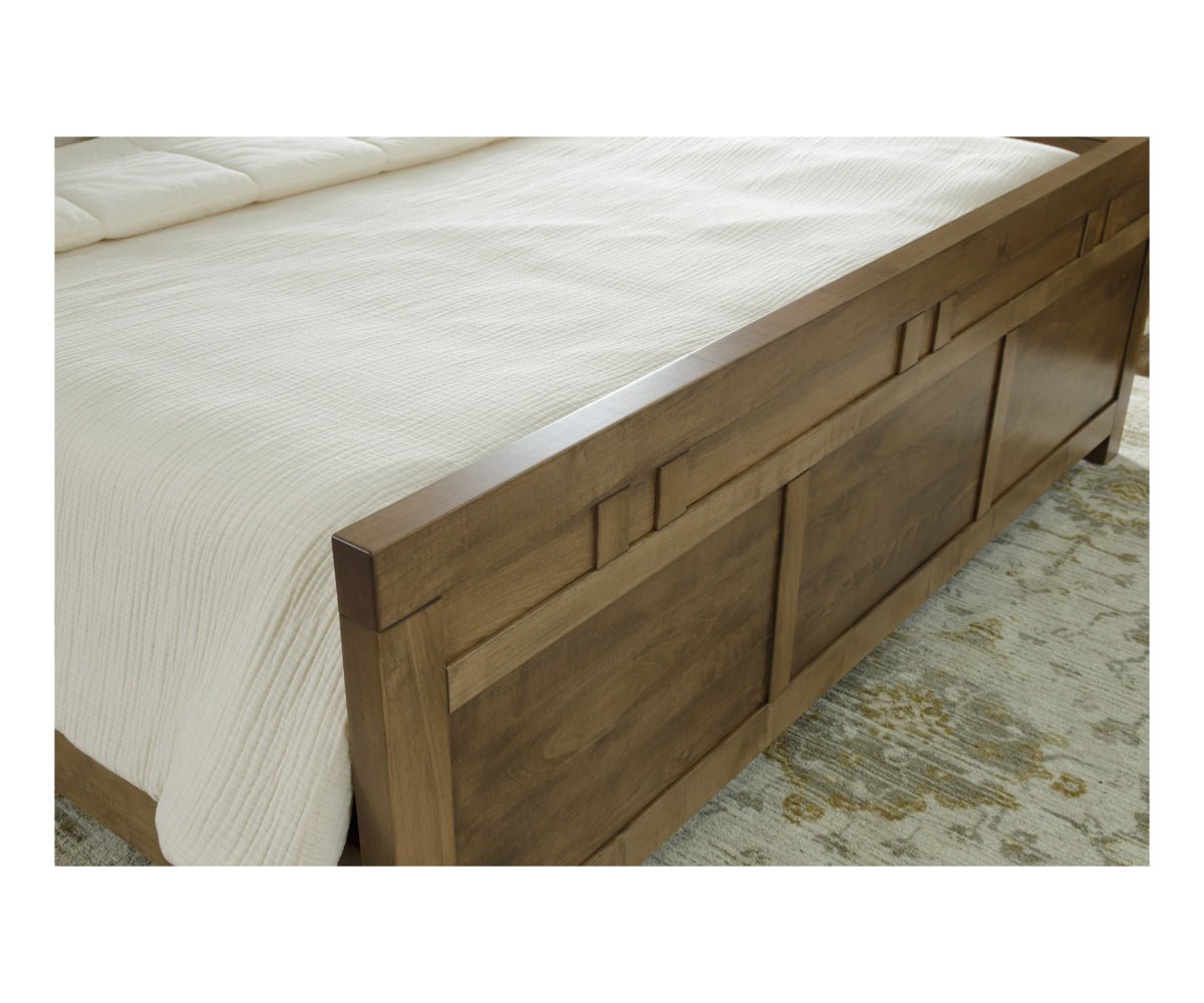 Close-up of the maple bed footboard showing three raised panels, block inlay detailing and a rounded top rail