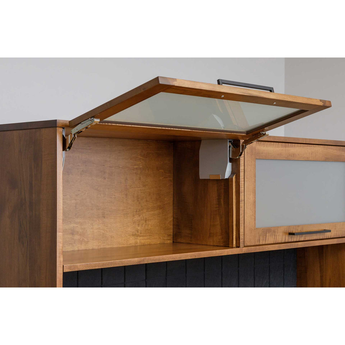 Frosted glass hutch door raised on lift hinges above an open shelf, shown in a warm birch finish