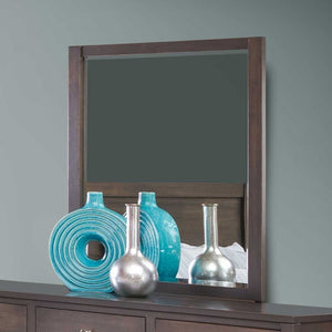 Dark wood dresser mirror reflecting a bedroom, with turquoise ceramic and silver vases on the dresser below