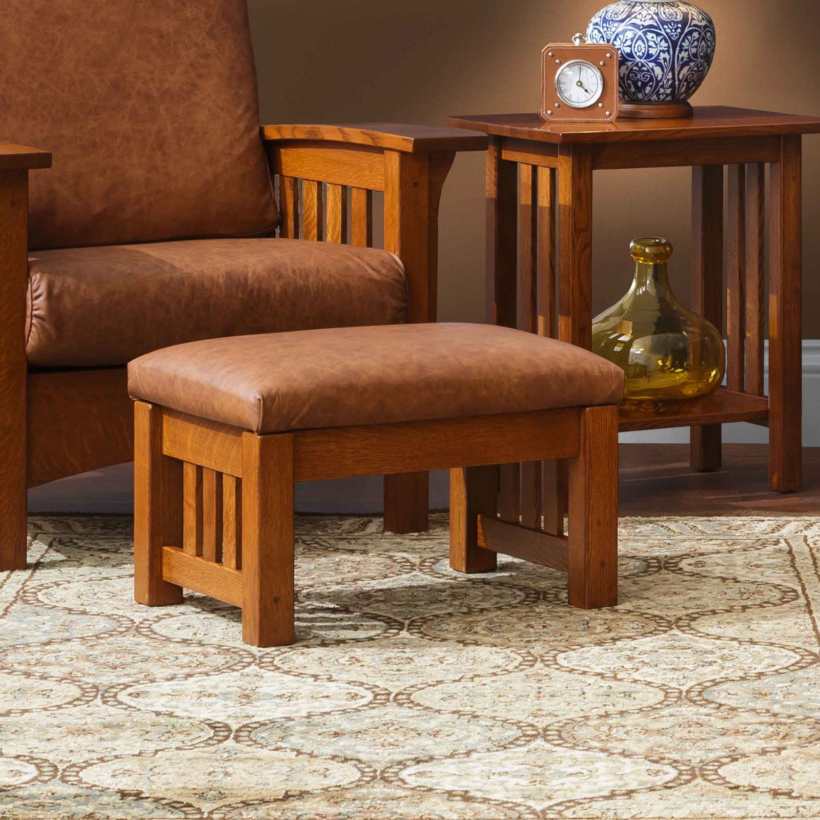 Small mission ottoman with light gray cushion and slatted oak legs on a patterned rug beside a matching chair