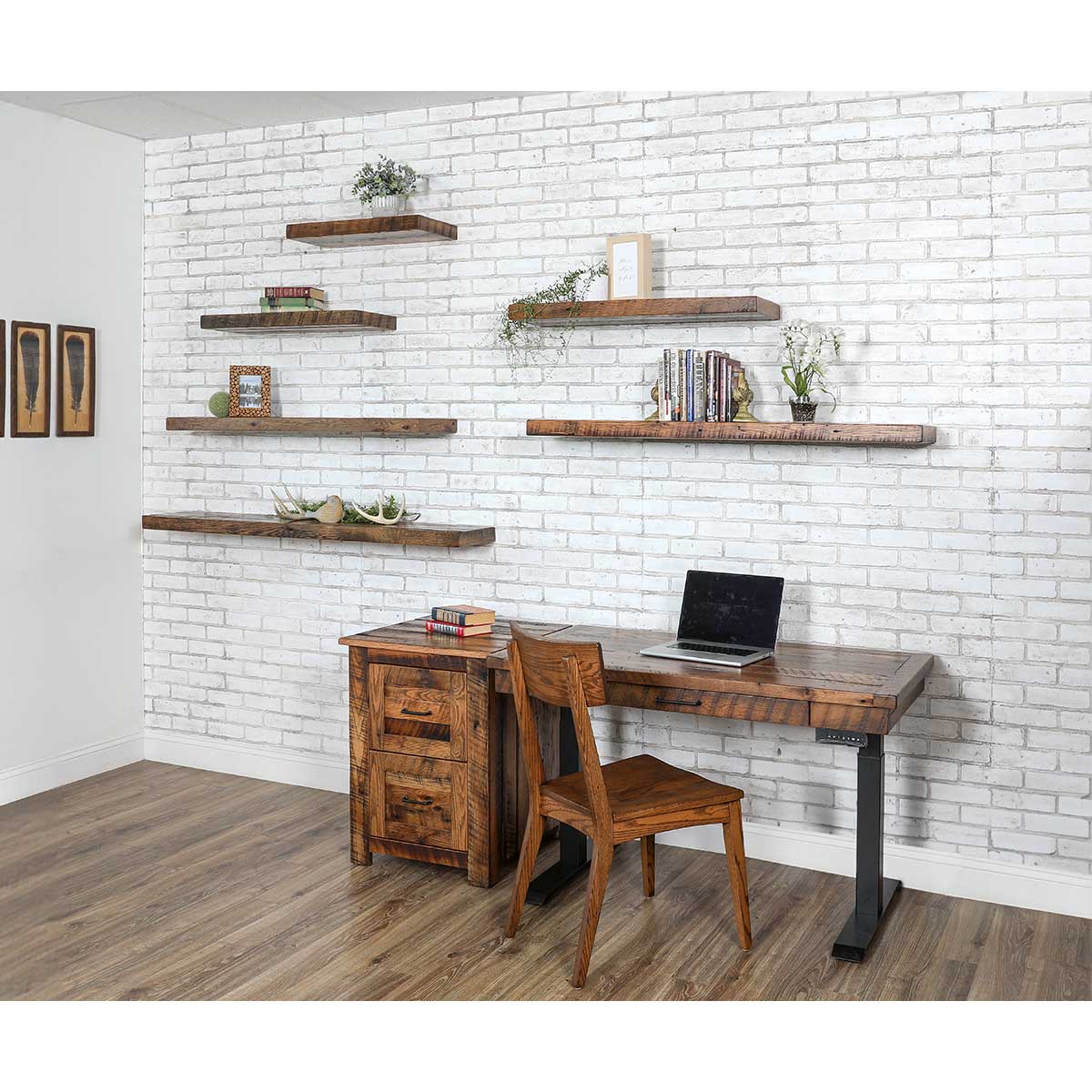 Six reclaimed wood floating shelves staggered on a whitewashed brick wall above a rustic standing desk