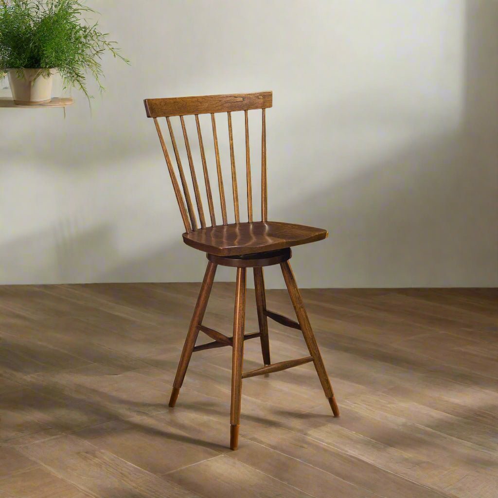 Walnut Windsor swivel bar stool with a spindle back and shaped seat standing on wide plank flooring