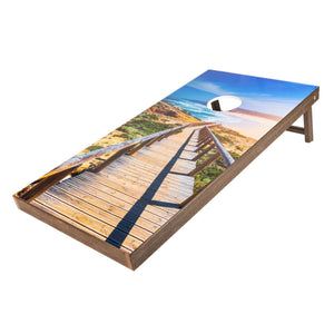 Beach boardwalk print cornhole board with dune path and ocean view on a brown wood frame