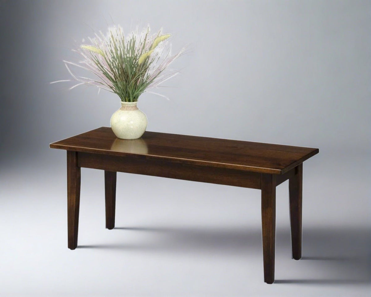 Petite Shaker coffee table in a walnut brown finish with plank top, slim apron and tapered legs, topped with a vase of dried grass