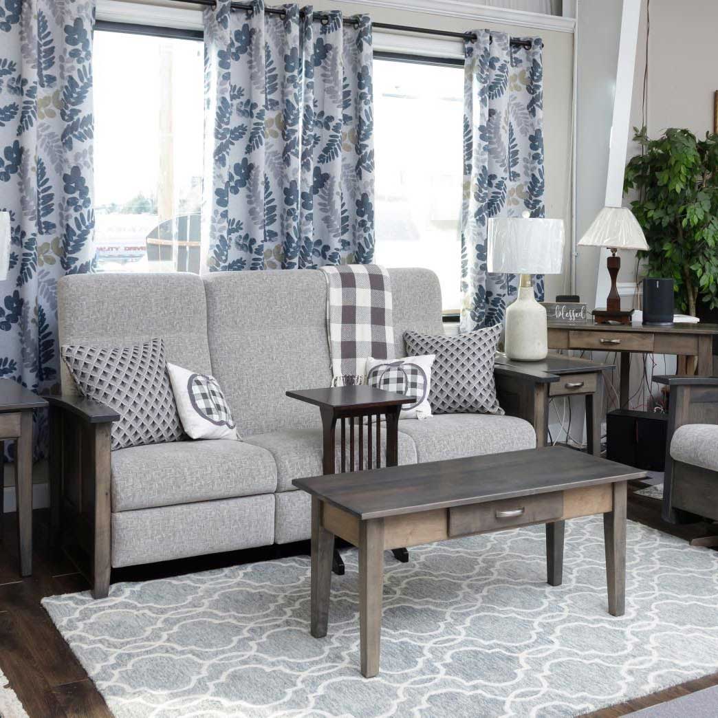 Gray stained Shaker coffee table with a center drawer, brushed nickel bar pull and tapered legs on light wood flooring