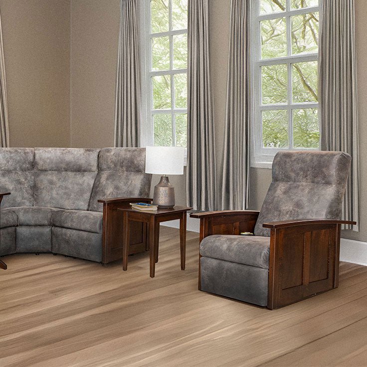 Gray reclining chair with paneled cherry arms beside a matching sectional and end table in a sunlit living room