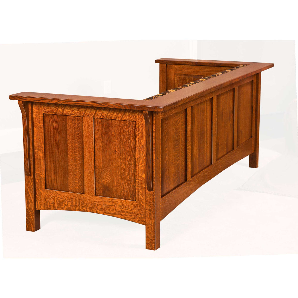 Angled rear view of a quartersawn oak paneled club sofa showing the panel back and floral cushions inside