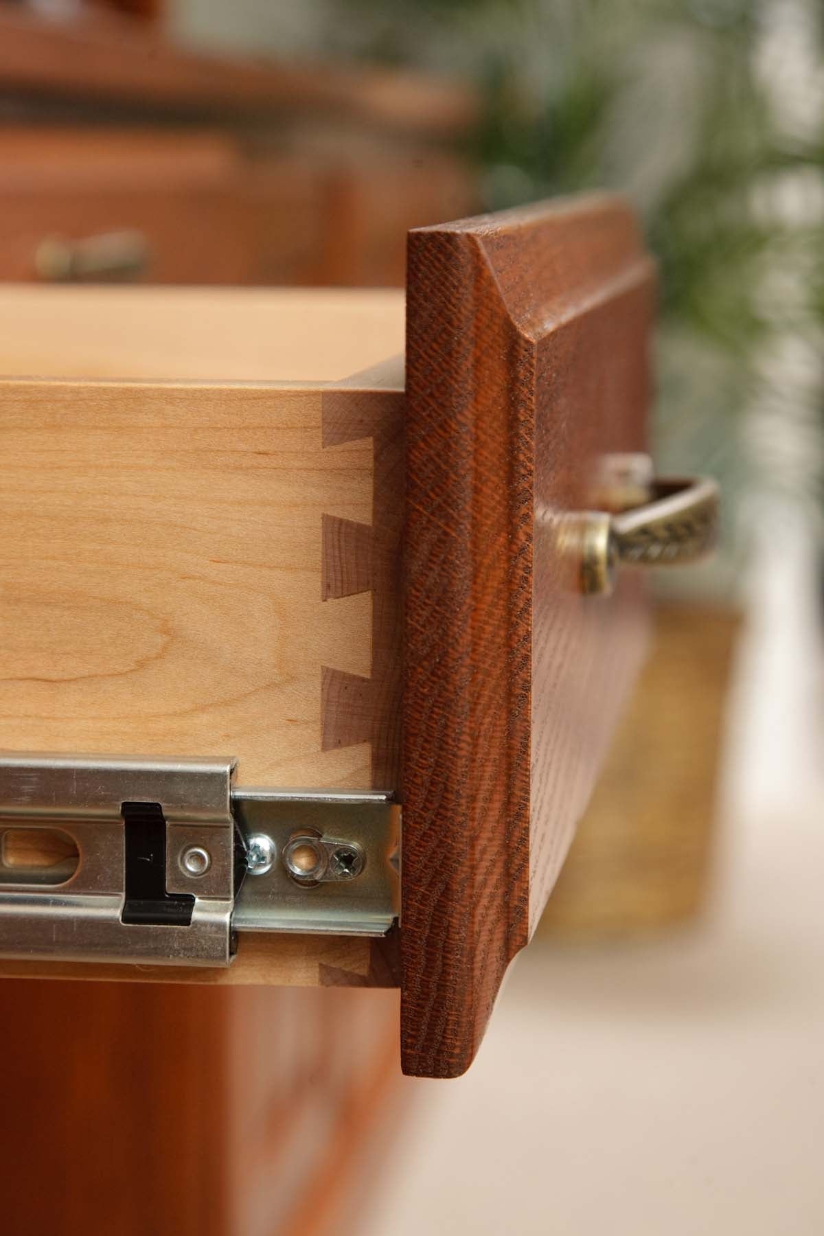 Macro of an open drawer showing hand-cut maple dovetail joinery, oak drawer front and ball-bearing slide