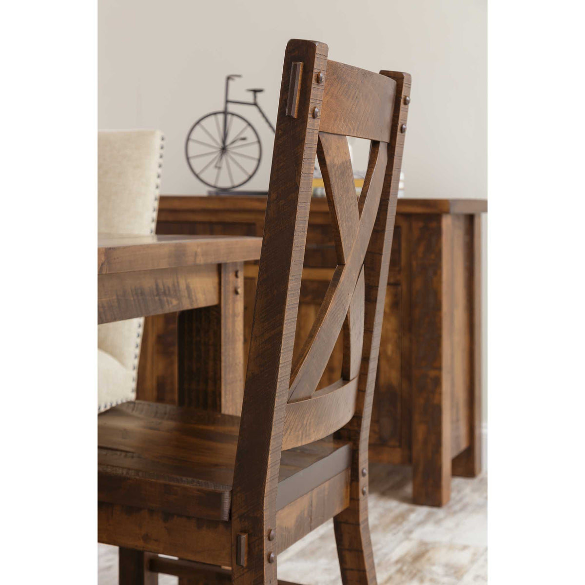 Angled rear detail of a rustic X back dining chair showing sawmarked wood, bolts and curved rear posts