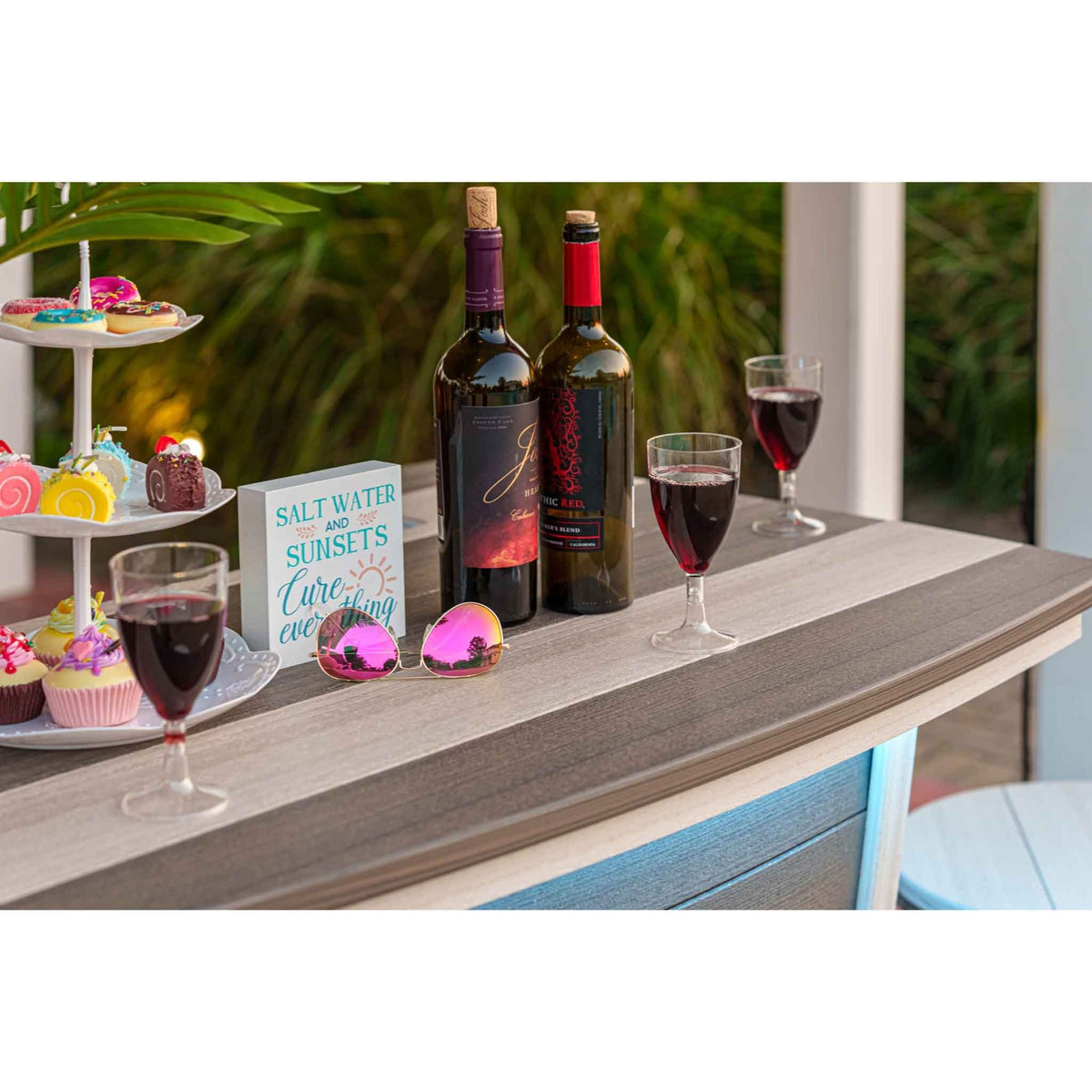 Close-up of the boat bar's driftwood gray poly bar top styled with wine bottles, glasses and desserts