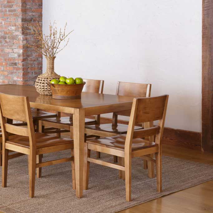 Rectangular maple dining table with four flat back modern chairs on a woven rug in a rustic dining room